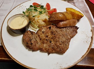 Beef chop with fried potatoes and salad on a white plate