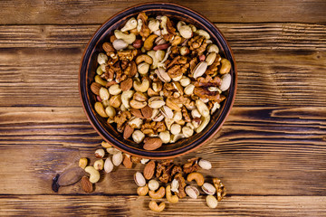 Various nuts (almond, cashew, hazelnut, pistachio, walnut) in ceramic plate on a wooden table. Vegetarian meal. Healthy eating concept. Top view