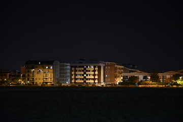 Fototapeta premium Night Illuminated City Houses Over the Garden