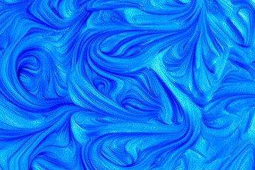 Close up liquid luxury blue metallic glitter paint swirls to make an abstract textured background