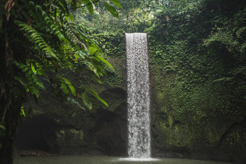 Small secret waterfall Tibumana in Bali, Indonesia. Popular tourist landmark in green lush jungle. Nobody around, nature background.