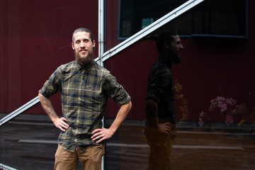 young man with beard and gauged pierced ears on black glass wall background