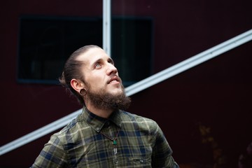 young man with beard and gauged pierced ears on black glass wall background