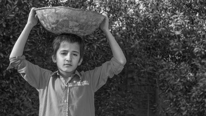 a very young orphan child is forced into child labor and working at a construction site and his expressions area full of pain  