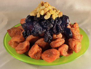 On a plate are apricots, prunes and raisins