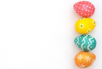 Colourful painted orange, blue, red and yellow Easter eggs on white background. Happy Easter holiday. Flat lay style with copy space.