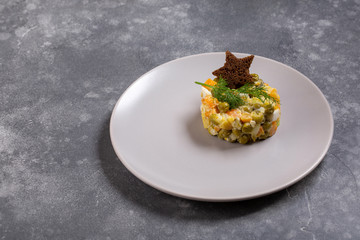 Traditional Russian Olivier salad decorated with toast star on gray table. Copy space.