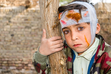 a cute injured child with sad expression and having bleeding bandage on his head