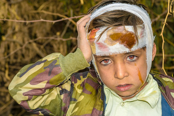 a cute injured child with sad expression and having bleeding bandage on his head