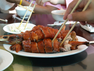 Human hand are using chopstick to take roasted duck