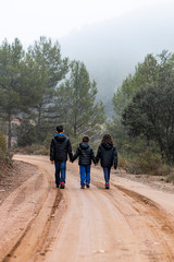 Obraz premium Three children holding hands on a foggy road