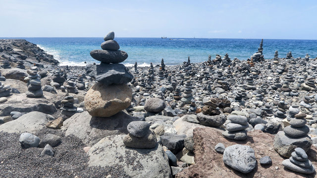 Promenade and pebble towers on the beaches of El Jard&iacute;n and El Beril beach.  of pebbles stacked on top of each other and round cobblestones build towers.