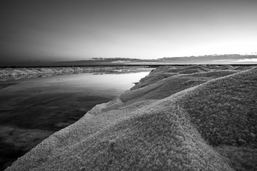 Nature reserve Saline Margherita di Savoia, Apulia, Italy: black and white image of  salt pan at sunset. Salt flats area for sea salt production. A salt marsh, an ecosystem on Adriatic sea.