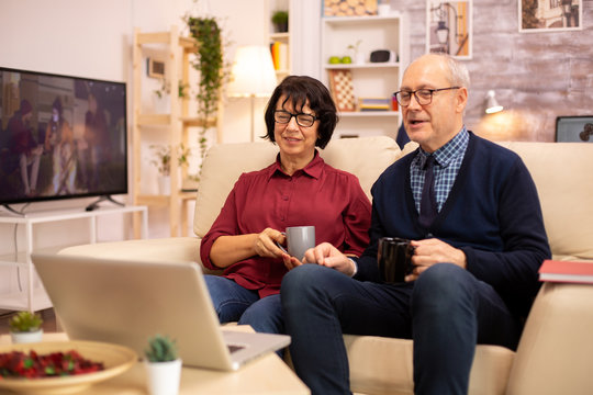 Elderly old couple using modern laptop to chat with their grandson