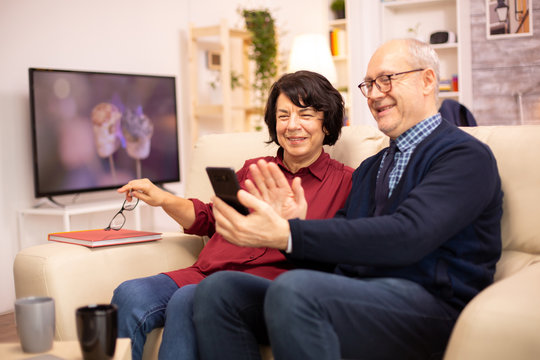 Old eldelry couple using a smartphone to talk with their family