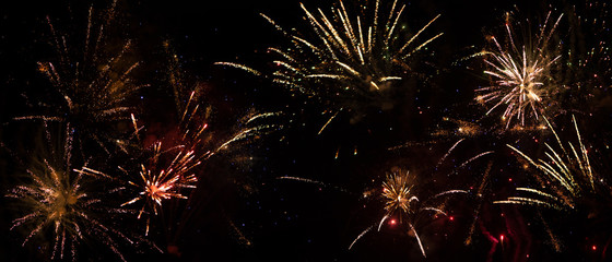 Feuerwerksraketen in verschiedenen Farben erleuchten den schwarzen Neujahrshimmel-Hintergrund für...
