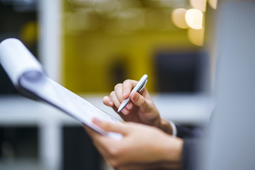 A man signs a contrac, legal or business agreements. Male hand with pen of young office worker makes notes. Business man  sitting at office desk and signing a document in modern office.