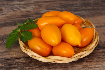 Yellow tomato heap in the wooden bowl
