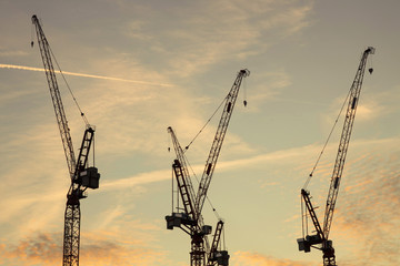 construction cranes against the backdrop of a colorful sunset