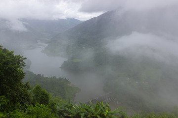 breathtaking landscape of a mountain valley in which a river flows and a dam stands in the fog