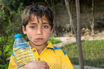 a thirsty boy is holding a bottle of sweet water cause of drinking water crises and shortage with...