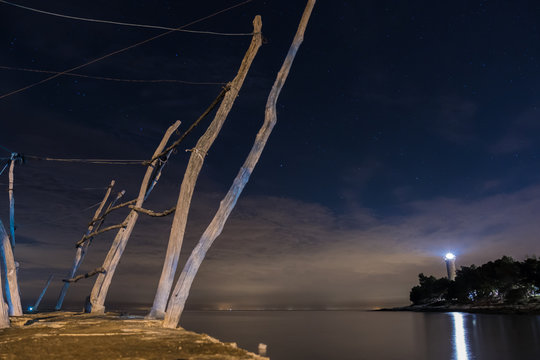 Long exposure night photo of wooden cranes of dock and lighthouse of Savudrija, Croatia