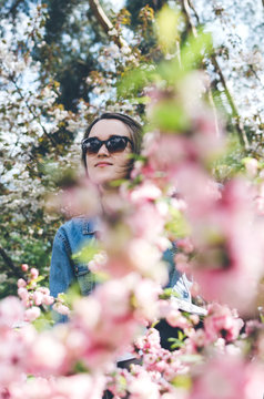 Woman in sunglass in blooming sakura garden