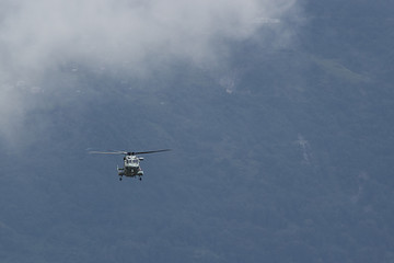 Obraz na płótnie Canvas military helicopter flying against the background of mountains and clouds
