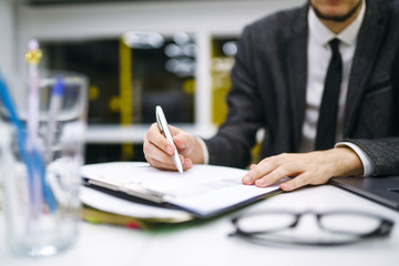 Pen in office worker hand. Close up of the hands of a businessman in a suit signing or writing a...