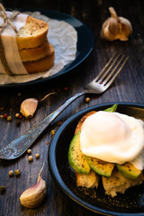 Food composition with poached egg, crouton, avocado and garlic. Sandwich on a blue plate and a fork nearby. Healthy Eating. For a postcard or magazine cover.