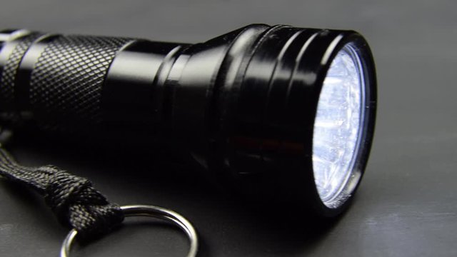 Black flashlight torch lying on a black table surface