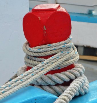 Red wood ship's capstan with rooes of different sizes attached with white and blue background