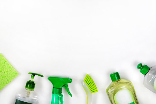 Detergents in green plastic bottles for housekeeping. Сleaning accessories. Top view of cleaning supplies on white background. Close up.