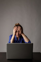 Young woman in blue with laptop. Overwork.