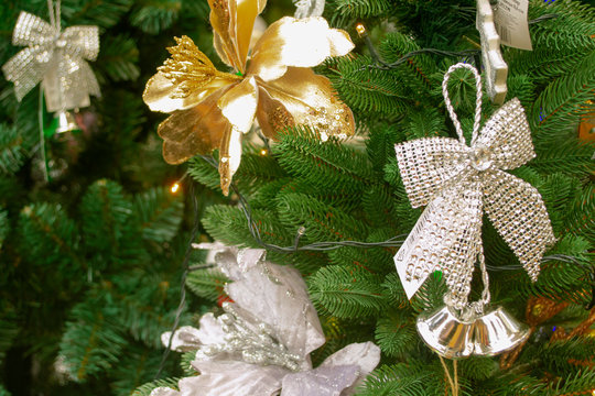 Christmas arrangement in golden and silver with pine twigs, poinsettia flowers and silk shining ribbon on spruce texture