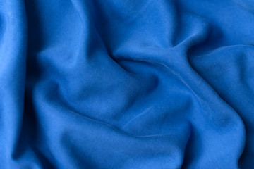 Fototapeta premium Blue fabric texture background. Textile cloth colored in trend classic blue color of the year 2020. Classic Blue Pantone color. Shallow depth of field, selective focus