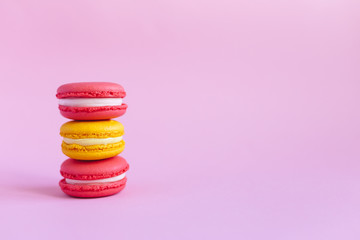Three tasty french macarons on pink background. Pink and yellow macarons.