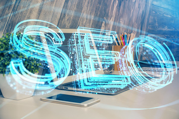 Multi exposure of table with computer and seo drawing hologram. Search optimization concept.