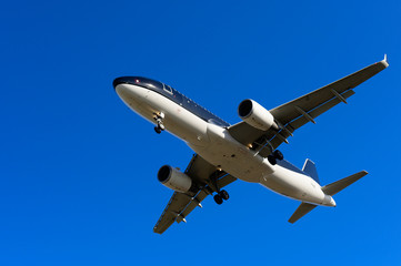 Fototapeta na wymiar Airplane fly overhead against blue sky