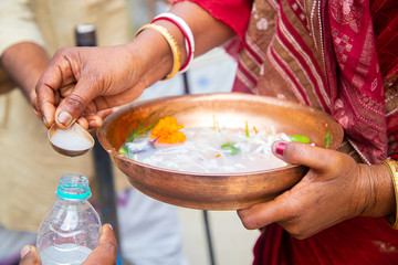 Woman in red mekhla holding religious offering