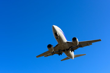 Fototapeta na wymiar Overhead aircraft landing with blue sky