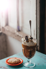 An oatmeal cookie next to a coffee drink