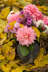 flowerpot with autumn flowers,stands a jug with flowers in yellow leaves in autumn