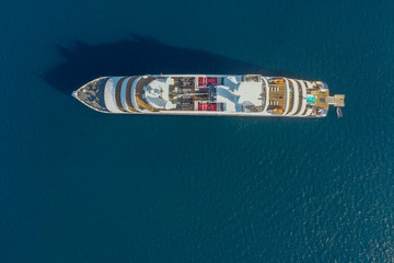 Top down aerial image large holiday cruise ship in the middle of the ocean with the small speed boat across around.