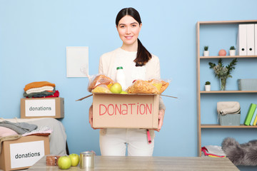 A young girl volunteer collects a box of donations for those in need of an interior room.