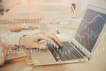 Double exposure of stock market graph with man working on laptop on background. Concept of financial analysis.