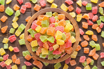 candied fruit, colorful cubes in wooden bowl, top view.