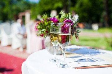 Beautiful wedding set decoration in the outdoor ceremony. Two glasses with champagne.