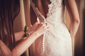 Gorgeous, bride in white dress, preparing for the wedding. Woman puts on a dress.