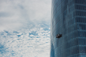10/17/2019 - Bilbao, Spain: skyscraper with washing gondola on sky background. Modern urban buildings concept. Climbing window cleaner in skyscraper. Dangerous work. Worker on office centre facade. © Nataliia